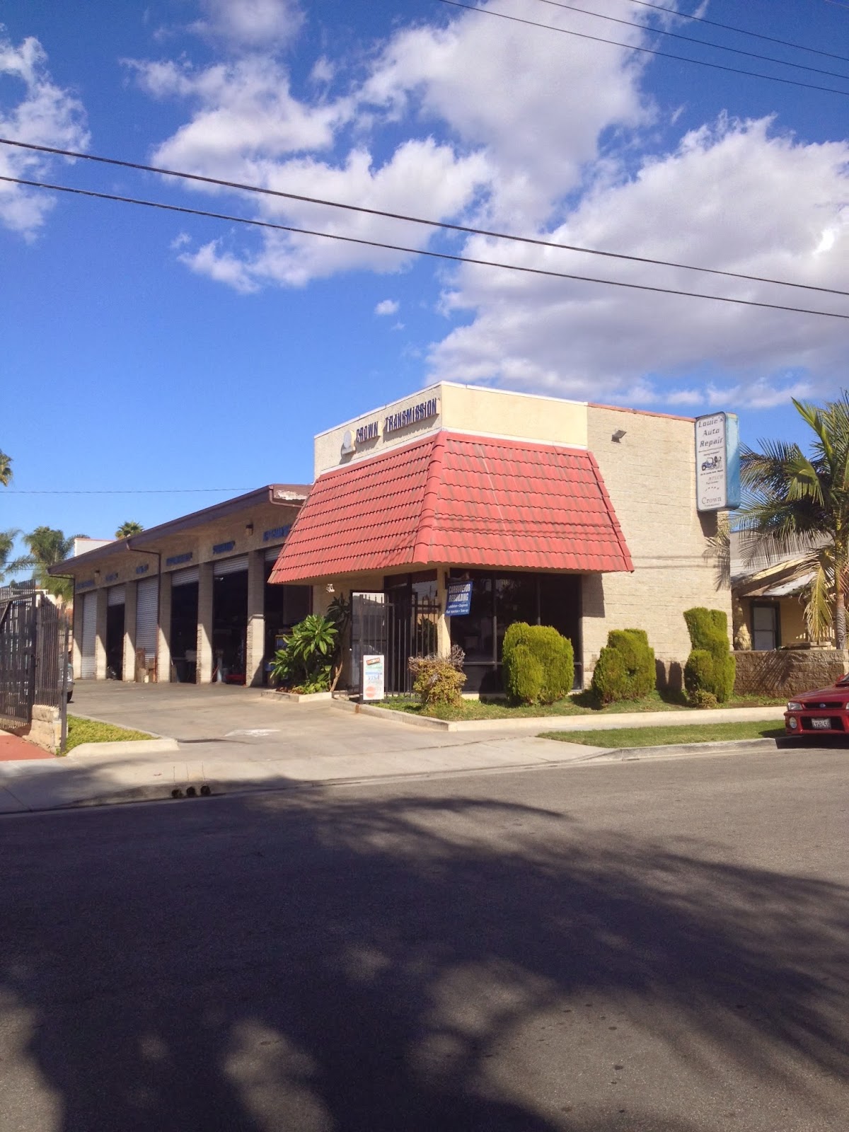 Louie's Auto Repair on E 1st Ave, red tile awning, open repair bays and the Crown Transmission sign across the front